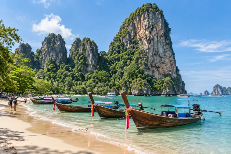 Longtail boats below limestone cliffs on a Krabi beach